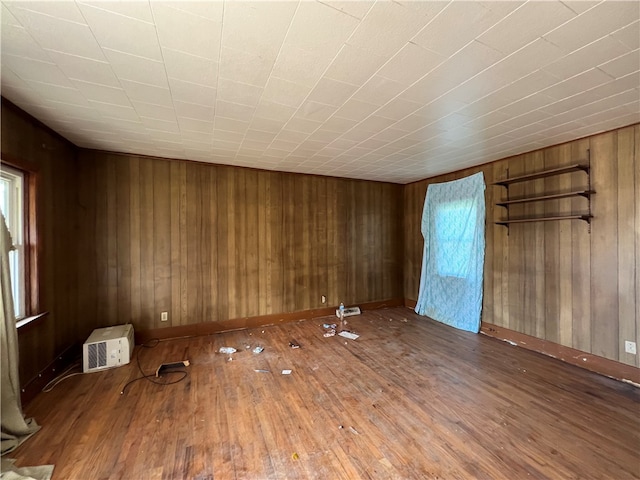 unfurnished room with hardwood / wood-style flooring and wooden walls