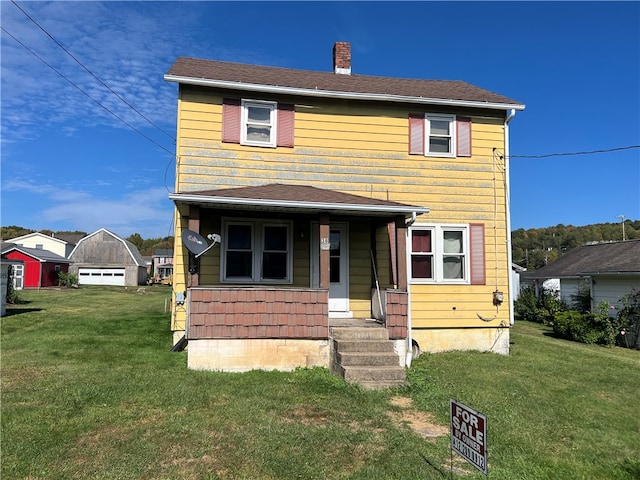 view of front of home with covered porch, a front yard, and a garage