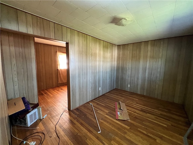 unfurnished room with hardwood / wood-style flooring and wood walls