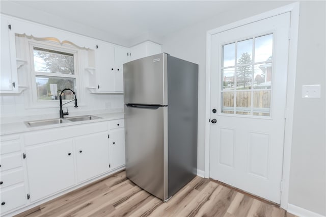 kitchen featuring a wealth of natural light, sink, white cabinetry, and stainless steel refrigerator