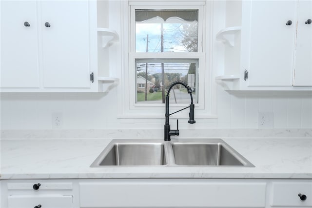 kitchen with light stone counters, tasteful backsplash, sink, and white cabinets