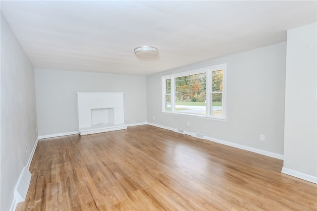 unfurnished living room featuring light hardwood / wood-style flooring and a brick fireplace