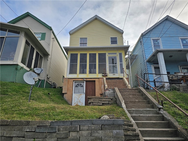 rear view of property featuring a yard and a sunroom