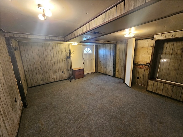 basement featuring wood walls and dark carpet