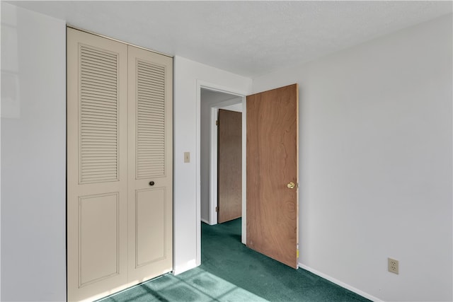 unfurnished bedroom featuring dark carpet, a textured ceiling, and a closet