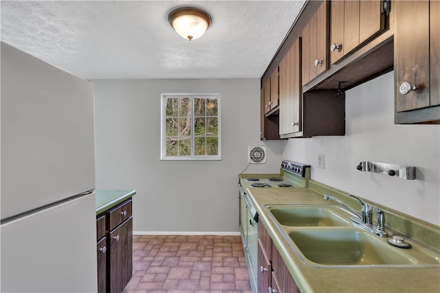 kitchen featuring a textured ceiling, stainless steel electric range, sink, and white refrigerator