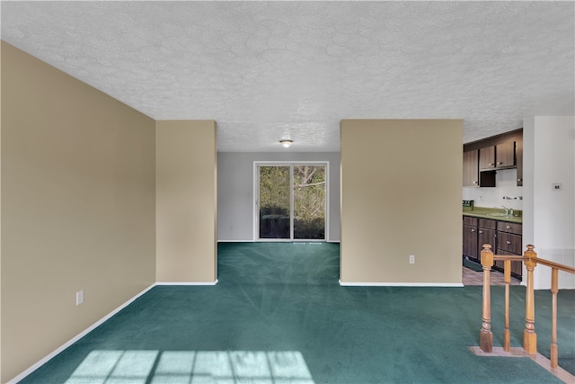 unfurnished living room featuring a textured ceiling, sink, and dark colored carpet