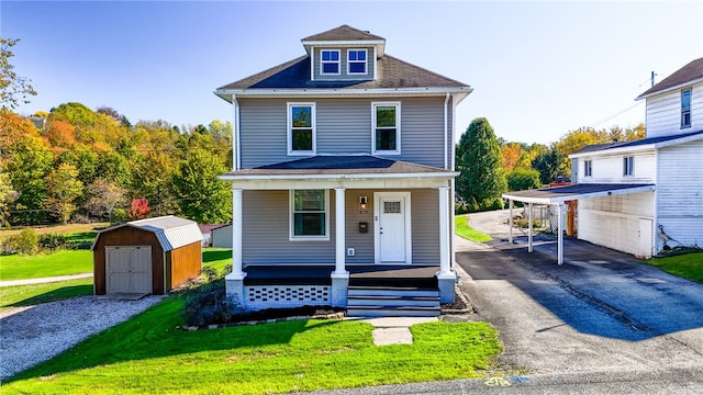 view of property with covered porch, a front lawn, and a storage unit