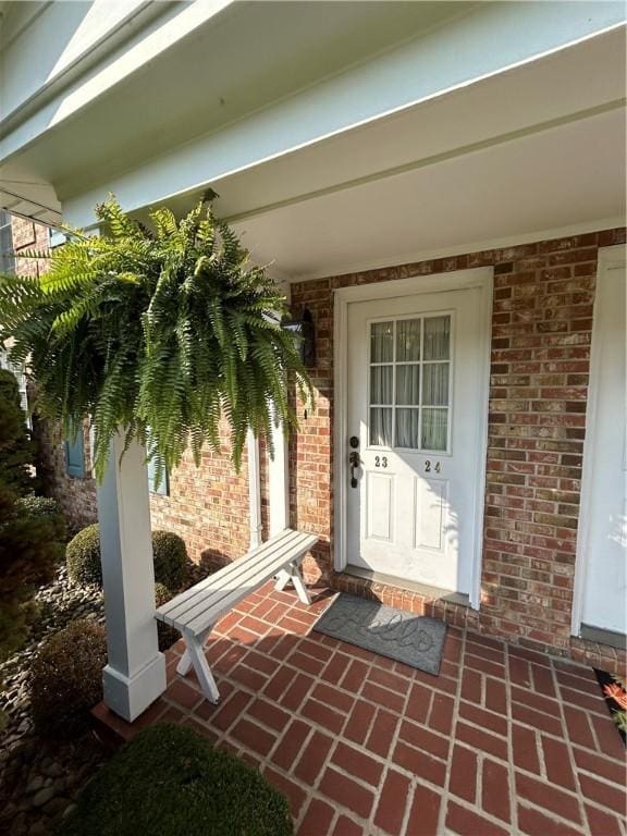 view of exterior entry featuring a porch and brick siding