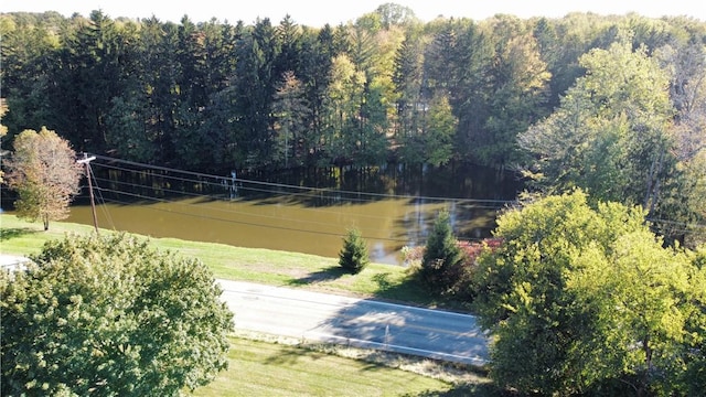 view of tennis court with a yard and a view of trees