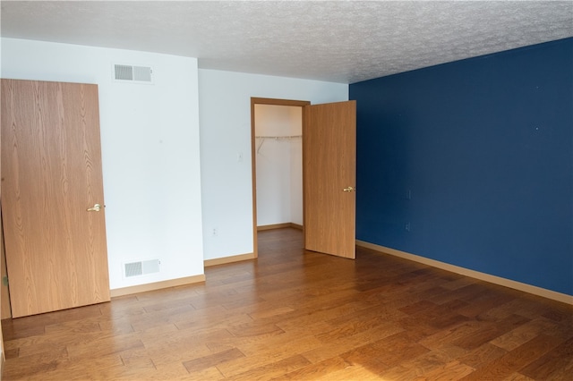 unfurnished room with a textured ceiling and wood-type flooring