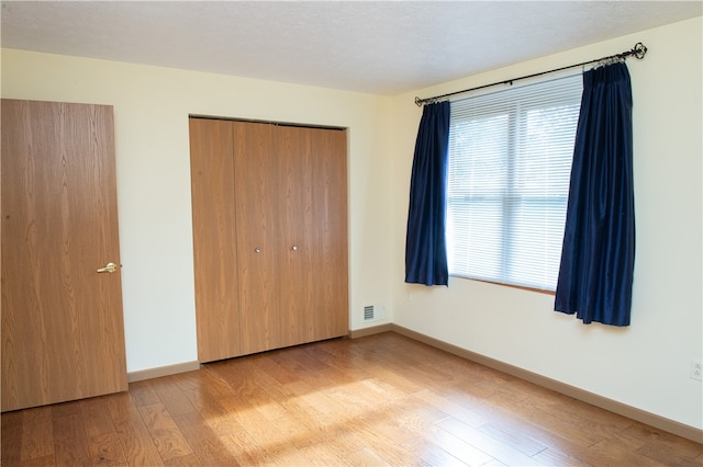 unfurnished bedroom featuring a closet, a textured ceiling, and light wood-type flooring