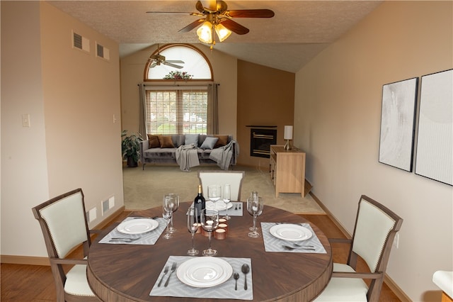 dining space featuring light hardwood / wood-style flooring, a textured ceiling, ceiling fan, and vaulted ceiling