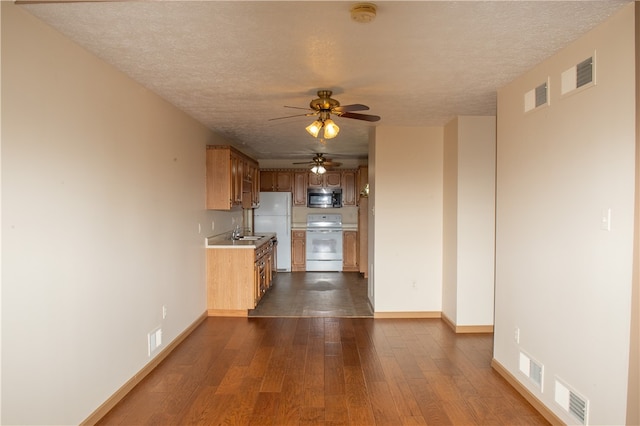 kitchen featuring ceiling fan, a textured ceiling, dark wood-type flooring, sink, and white appliances