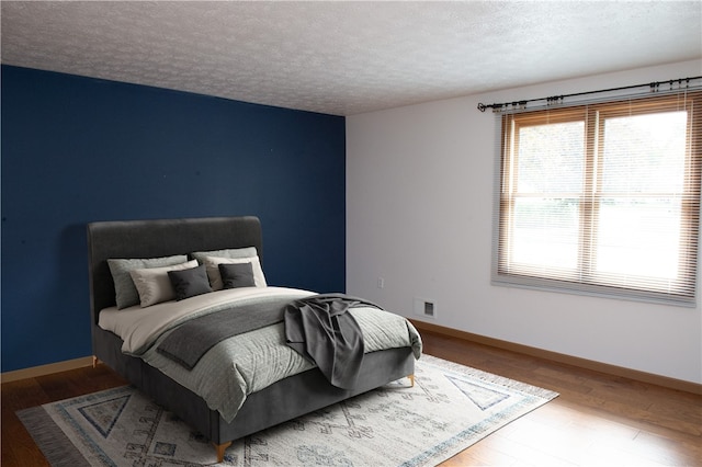 bedroom with hardwood / wood-style flooring and a textured ceiling