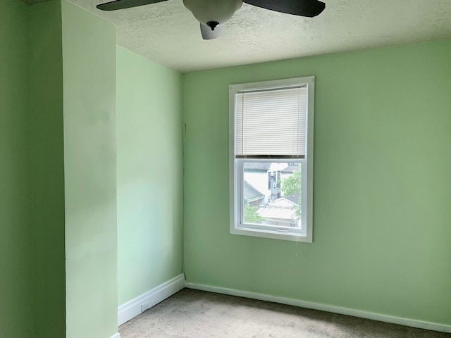 carpeted spare room featuring a textured ceiling, a healthy amount of sunlight, and ceiling fan