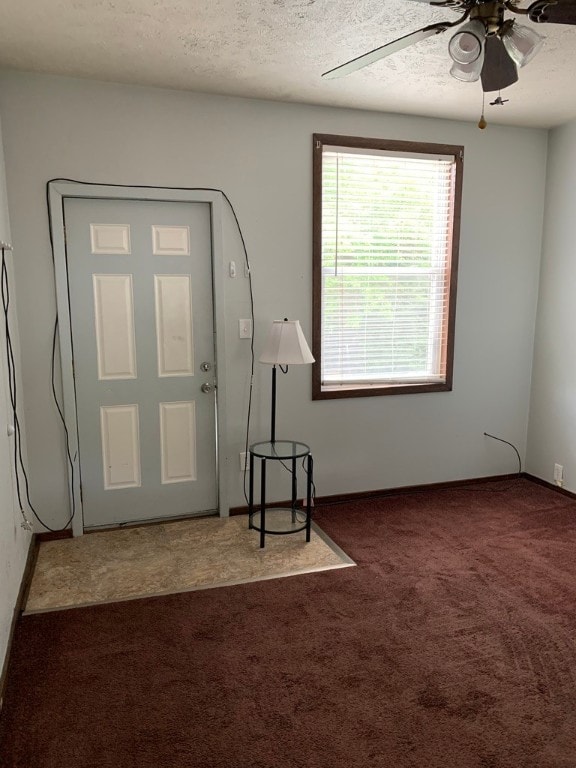 carpeted foyer entrance with a textured ceiling and ceiling fan