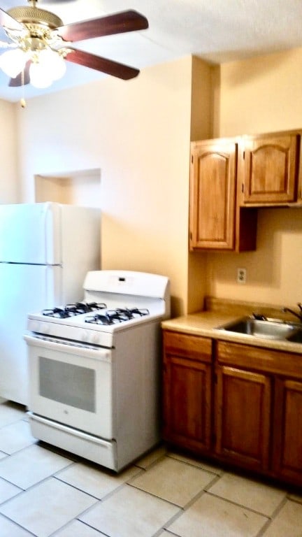 kitchen with light tile patterned floors, ceiling fan, sink, and white range with gas stovetop