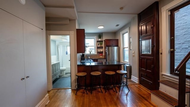 kitchen featuring dark hardwood / wood-style flooring, a kitchen breakfast bar, and stainless steel refrigerator