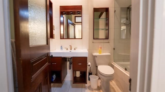 full bathroom with tile patterned floors, toilet, backsplash, tile walls, and washtub / shower combination