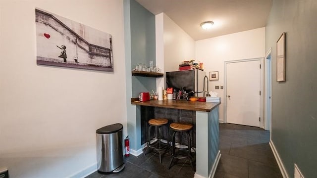 bar featuring dark tile patterned flooring, butcher block countertops, and black fridge