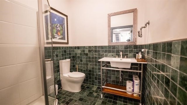 bathroom with toilet, tile walls, and sink