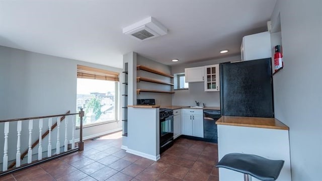 kitchen featuring black appliances, sink, dark tile patterned floors, and white cabinets