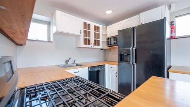 kitchen featuring butcher block countertops, black appliances, and white cabinetry