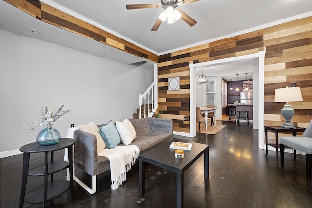 living room featuring wooden walls, crown molding, and dark wood-type flooring