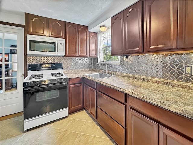 kitchen with decorative backsplash, white appliances, light stone counters, and sink