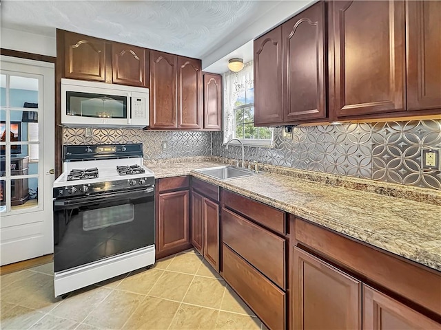 kitchen with light stone countertops, sink, range with gas cooktop, and backsplash