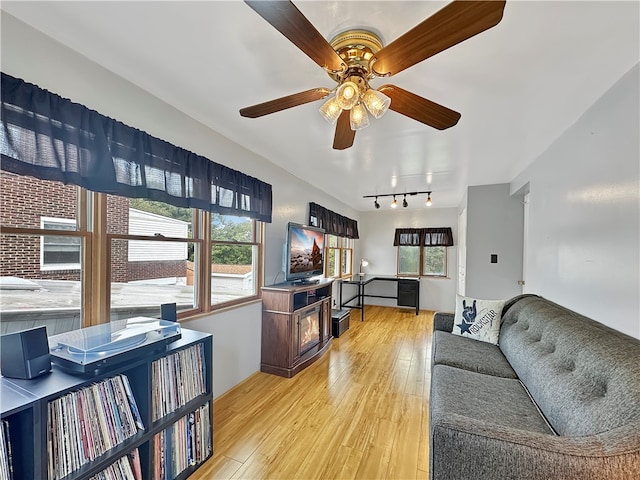 living room featuring ceiling fan, rail lighting, and light hardwood / wood-style flooring