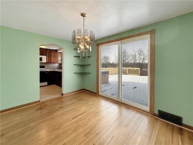 unfurnished dining area with sink, a notable chandelier, and light wood-type flooring