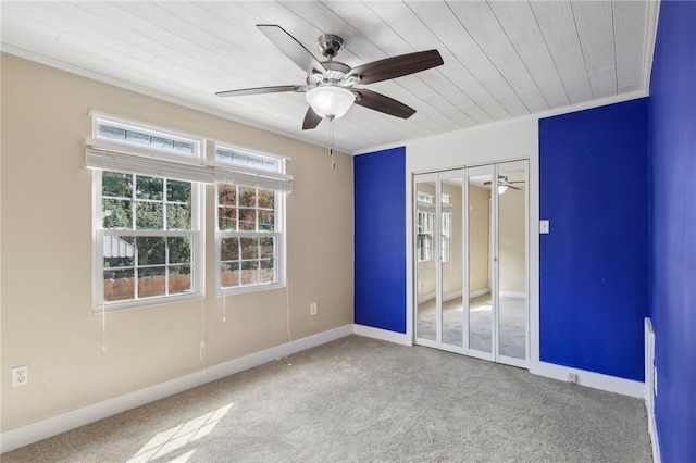 carpeted empty room featuring ceiling fan, wooden ceiling, and crown molding