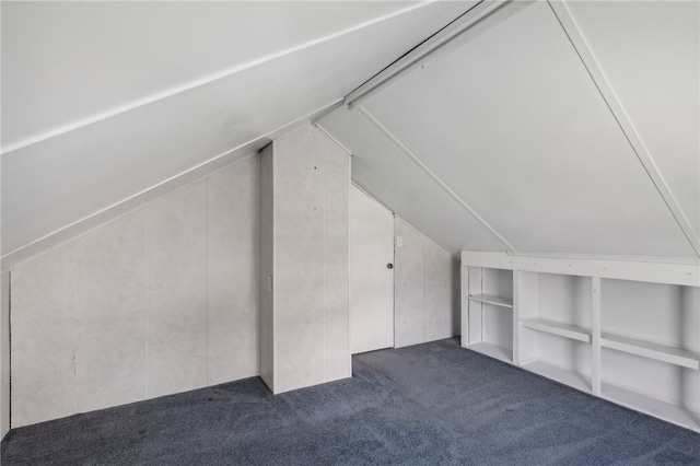 bonus room with dark colored carpet and vaulted ceiling