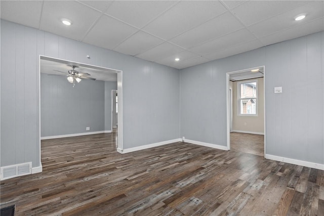 unfurnished room with ceiling fan, a drop ceiling, and dark wood-type flooring