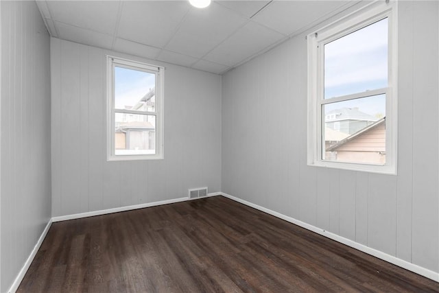 spare room with a drop ceiling and dark hardwood / wood-style floors