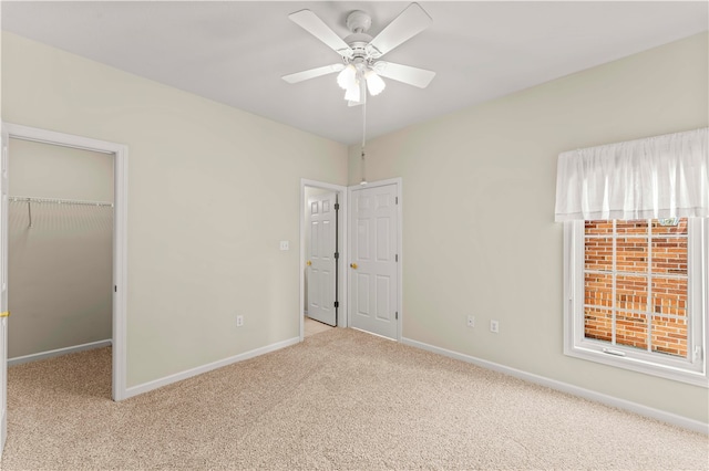 unfurnished bedroom with light colored carpet, ceiling fan, a closet, and a walk in closet