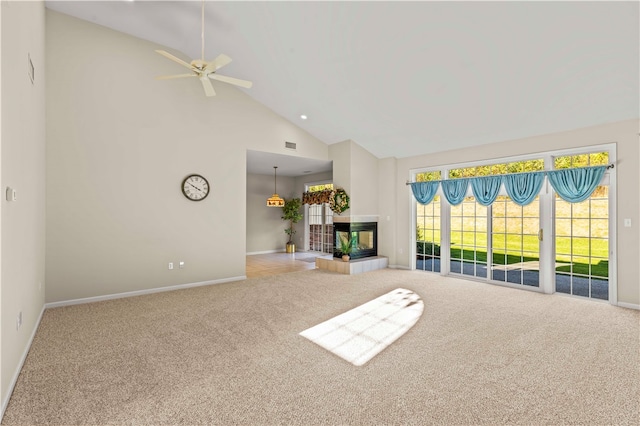 unfurnished living room with a tile fireplace, light colored carpet, high vaulted ceiling, and ceiling fan