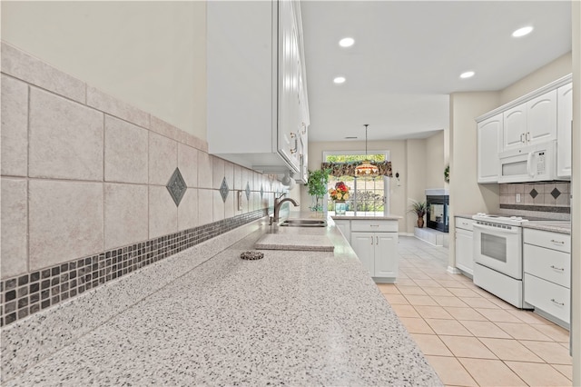 kitchen with white appliances, sink, decorative light fixtures, white cabinets, and light stone counters