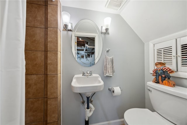 bathroom featuring toilet, sink, and vaulted ceiling