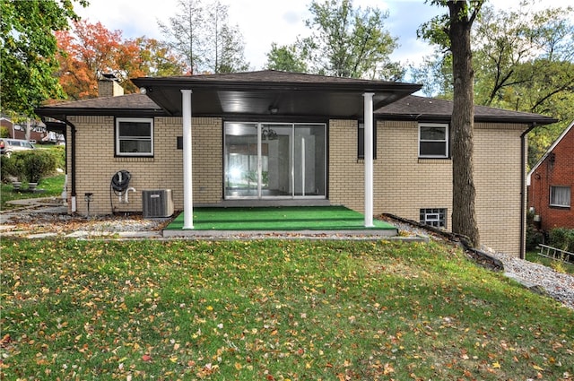 back of house featuring central air condition unit and a lawn