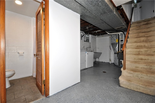 basement featuring sink, washer and dryer, and heating unit