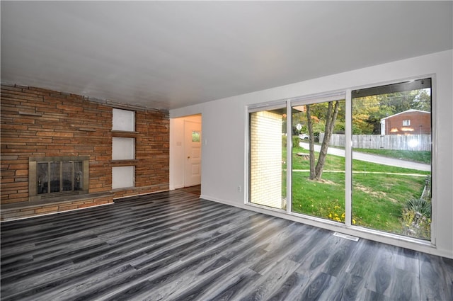 unfurnished living room with a stone fireplace and dark hardwood / wood-style flooring