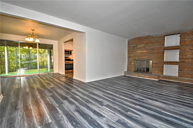 unfurnished living room featuring a stone fireplace, a chandelier, and dark hardwood / wood-style flooring