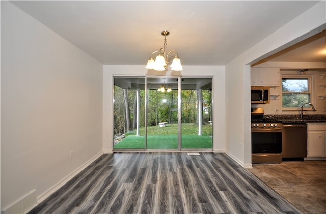 unfurnished dining area featuring sink, a notable chandelier, and dark hardwood / wood-style flooring