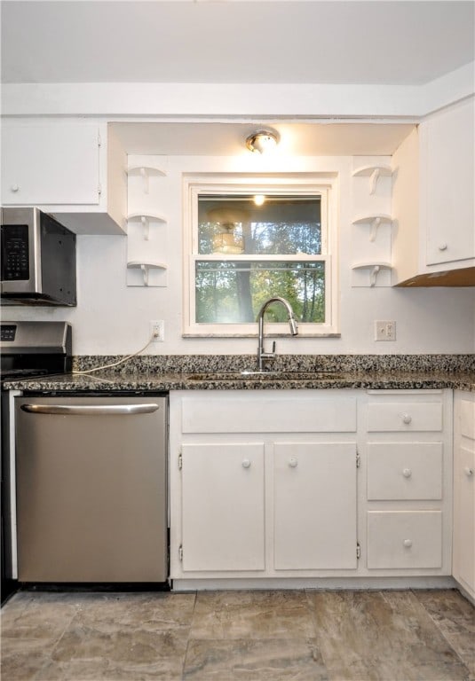 kitchen with white cabinets, stainless steel appliances, sink, and dark stone counters