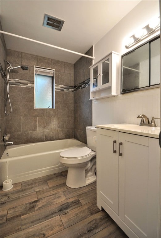 full bathroom with toilet, tiled shower / bath, hardwood / wood-style flooring, and vanity