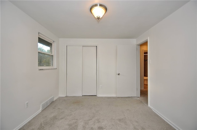 unfurnished bedroom with light carpet and a closet