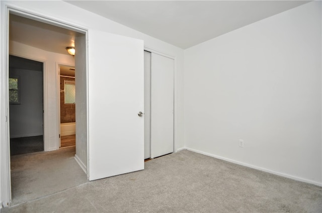 unfurnished bedroom with light colored carpet and a closet